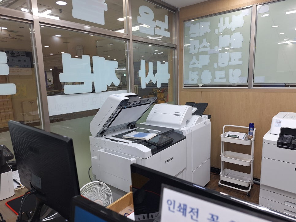 노은출력 매장 안에 놓인 흰색 복사기와 컴퓨터 작업 공간